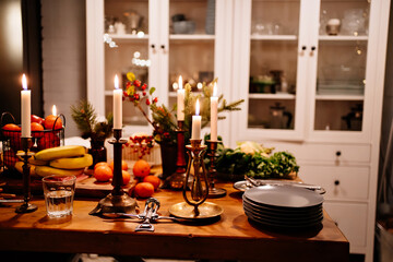 Low light. tangerines and apples in a metal basket and burning candles