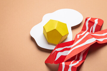 Paper craft food on beige or light brown background. Fried eggs and bacon slices cut from paper, top view. Creative breakfast or lunch flat lay concept
