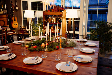 large square wooden table served for Christmas dinner. retro styled. Low light.
