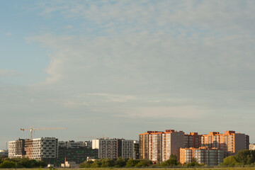 Fototapeta premium The city quarter of new buildings with bright facades in the middle of the greenery on the sky background.