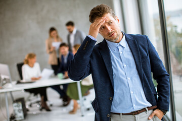 Business man feeling exhausted and stand at his working place in office