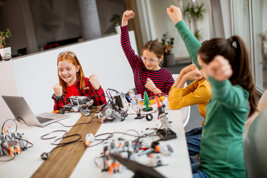 Happy kids programming electric toys and robots at robotics classroom