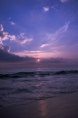 Fioletowo różowe niebo, krajobraz zachodzącego słońca na tle tropikalnej plaży i oceanu.
