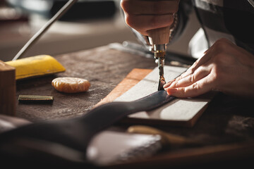 Leather handbag craftsman at work in a vintage workshop. Small business concept - 408835228