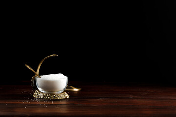 White sugar in an exclusive sugar bowl on a wooden table in an atmospheric dark kitchen 