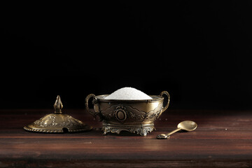 White sugar in an exclusive sugar bowl on a wooden table in an atmospheric dark kitchen 
