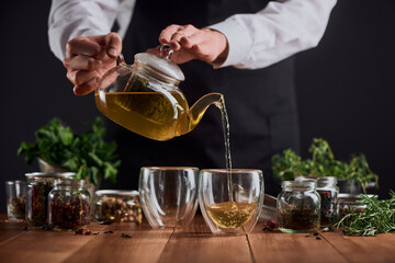 Tea master pouring hot tea from a pot into two glass cups