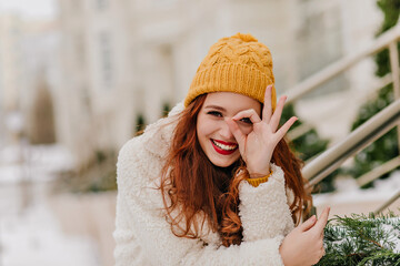 Merry female model having fun in winter. Pleased caucasian ginger woman laughing on nature background.