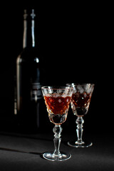 glasses with alcohol and a bottle on a black background