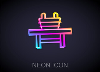 Glowing neon line Sauna bench with bucket icon isolated on black background. Vector.