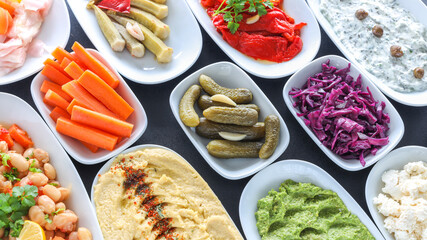 Top view of traditional Turkish and Greek vegetable dinner meze table. Turkish Cuisine Cold Appetizers ( with olive oil) in white plates. yogurt, avacado, humus, cheese and boiled kidney beans.