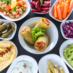 Traditional Turkish and Greek vegetable dinner meze table. with stuffed zucchini, colorful hummus, Cold Appetizers ( with olive oil) in white plates. yogurt, avocado, humus and cheese.