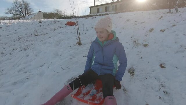 A child on a sledge riding down a snowy hill in slow motion