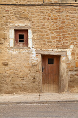 Fototapeta na wymiar Door and window in a house from medieval times, in the town of Uncastillo, in the Cinco Villas region, in the province of Zaragoza, Aragon, Spain.