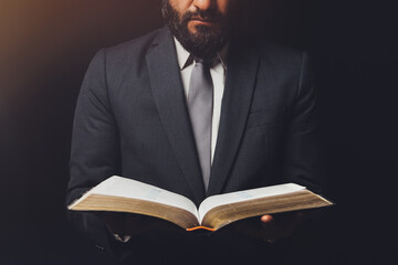 man in suit with an open bible on a black background