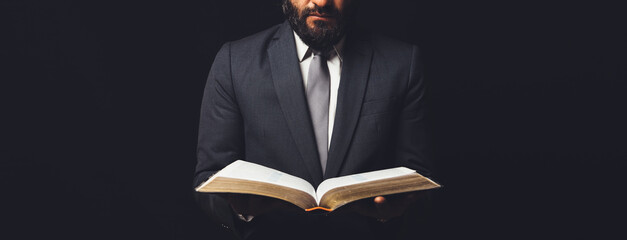 man in suit with an open bible on a black background