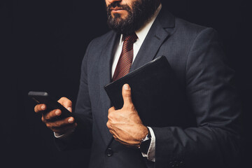man in suit holding a bible in his arm and with the cell phone in hand