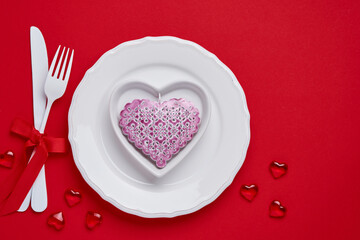 Valentines day background or concept with empty pink plate and whiteware on scarlet or red background. Top view flat lay with copy space.