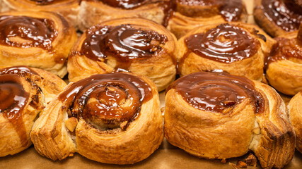 Homemade cinnamon buns with spices and caramel on parchment paper.