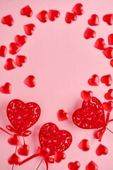 Festive composition with three red openwork hearts and small flying hearts on pink background. Top view, copy space. Valentine's day concept.