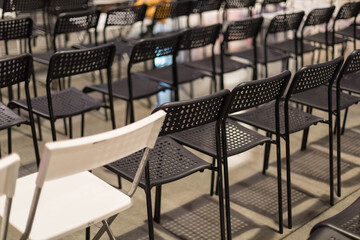 Rows of free chairs in the conference room or meetings. The chairs are black and oin white. Free room