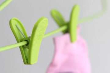 Green plastic clothes pegs on hanger with pink sock as background, it looks like a green heart. Love and valentine day concept
