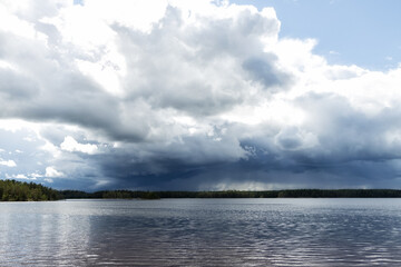 Naklejka na ściany i meble Landscape of a lake under dark storm clouds, moving waters reeds in the water. 