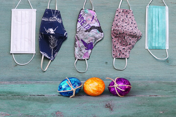 Corona und Ostern. Schutzmasken und Ostereier auf einem blauen Holzuntergrund