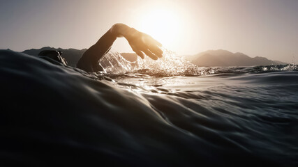 Athletic young man swimming at sea. Professional triathlon swimmer in ocean water. Young man...