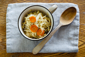 Sauerkraut – fermented preserved cabbage with carrots in bowl on a rustic table.