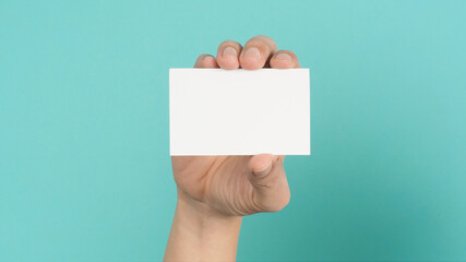 Male hand holding white blank card isolated on green or Tiffany Blue background.Empty space for text.
