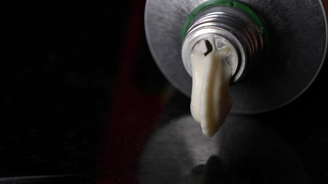 Detail view of mayonaise flowing out of a aluminium tube, isolated background.