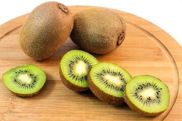 Delicious juicy ripe kiwi fruit whole and cut on a cutting board. 