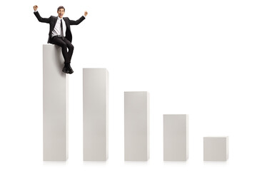 Businessman gesturing win and sitting on the highest column in a chart graph