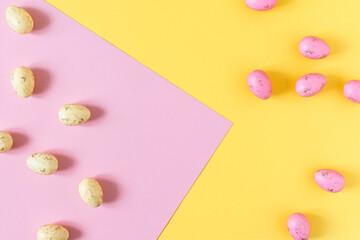 Yellow and pink Easter eggs on pastel pink and yellow background top view.