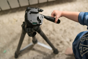 Tripod. Photography. Tripod adjustment. Hands are holding a tripod. Control levers. The kid takes...