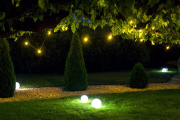 illumination park light garden with electric ground ball lantern with stone mulch and thuja bushes...