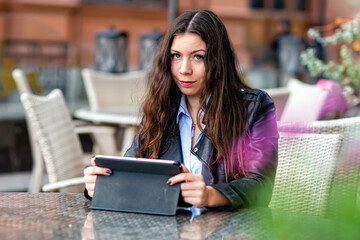 Fototapeta premium positive young female in casual clothes sitting in street cafe while working on remote project on digital tablet