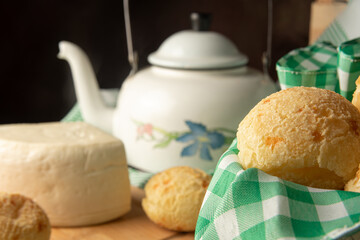 Cheese bread, Brazilian breakfast arrangement, cheese bread, white cheese, kettle and accessories, green towel, dark abstract background, selective focus.