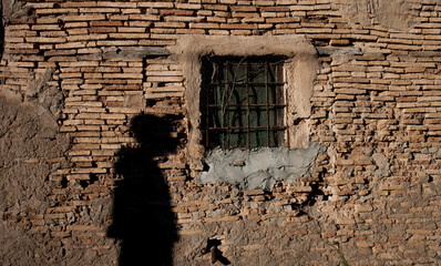 shadow of a man cast on the wall of an old brick house