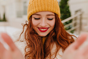 Excited ginger woman making selfie outdoor with sincere smile. Fascinating girl with long red hair enjoying winter.