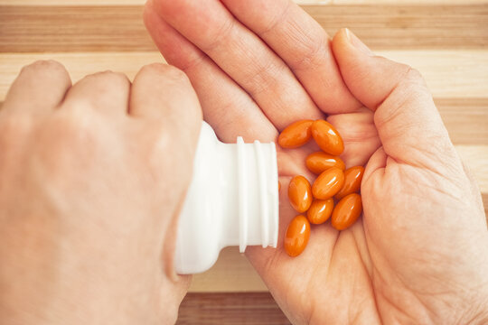 Woman taking Coenzyme Q10 pills out of a bottle