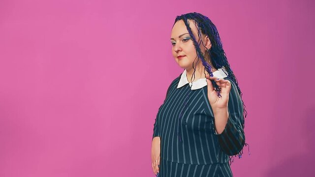 Stylish brunette with blue afro braids twists strands on her finger with a smile