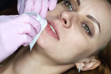 Young woman doing permanent lip makeup in a beautician's salon. Close-up photo