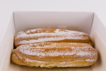 delicious French eclairs in a box with powdered sugar