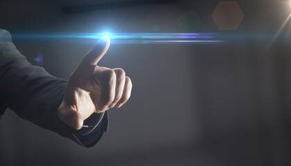 The hand of a man in a suit rolls with the finger of an invisible point. blue lighting at the tip of the finger as a symbol between idea and implementation through human technical skills