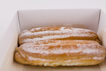 delicious French eclairs in a box with powdered sugar