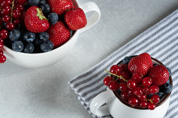 strawberries and blackberries in a bowl on light textured background.top view