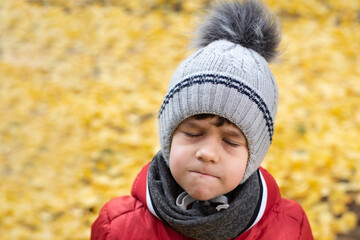 A little boy with closed eyes and pursed lips stands and is angry, sad, the boy was offended by older children and he now feels bad morally. Concept against bullying