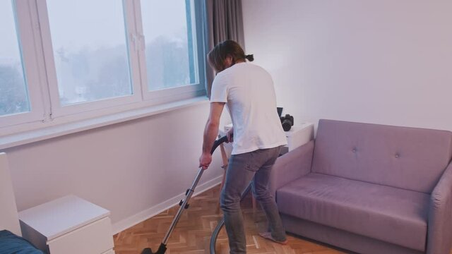 Young caucasian man dancing while using vacuum cleaner . High quality 4k footage